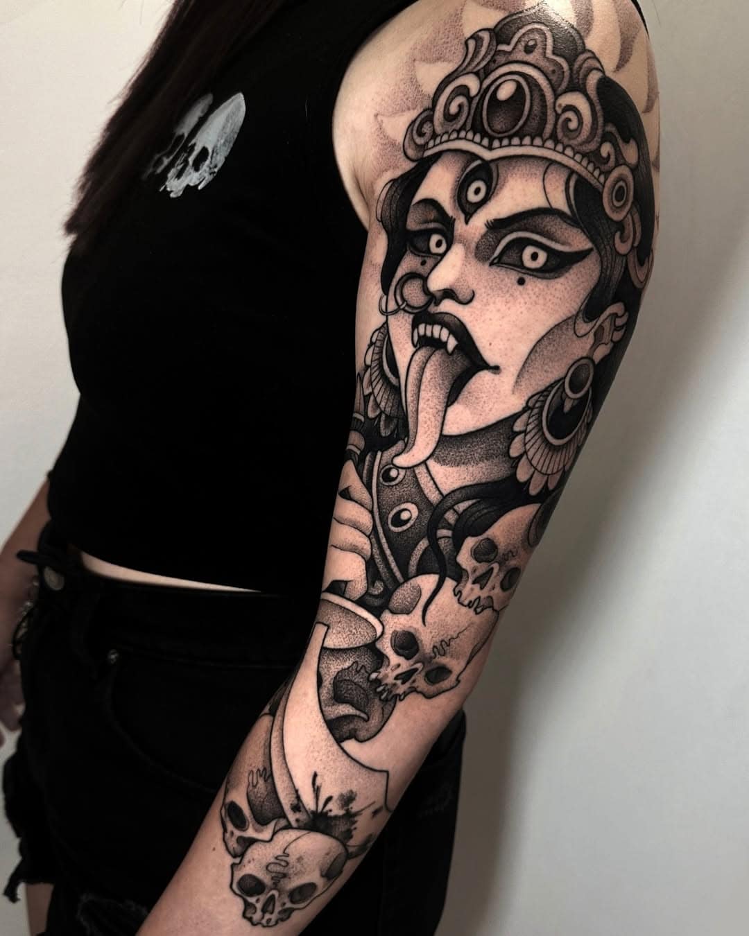 Detailreiches Tattoo eines mystischen Gesichts mit Totenköpfen.