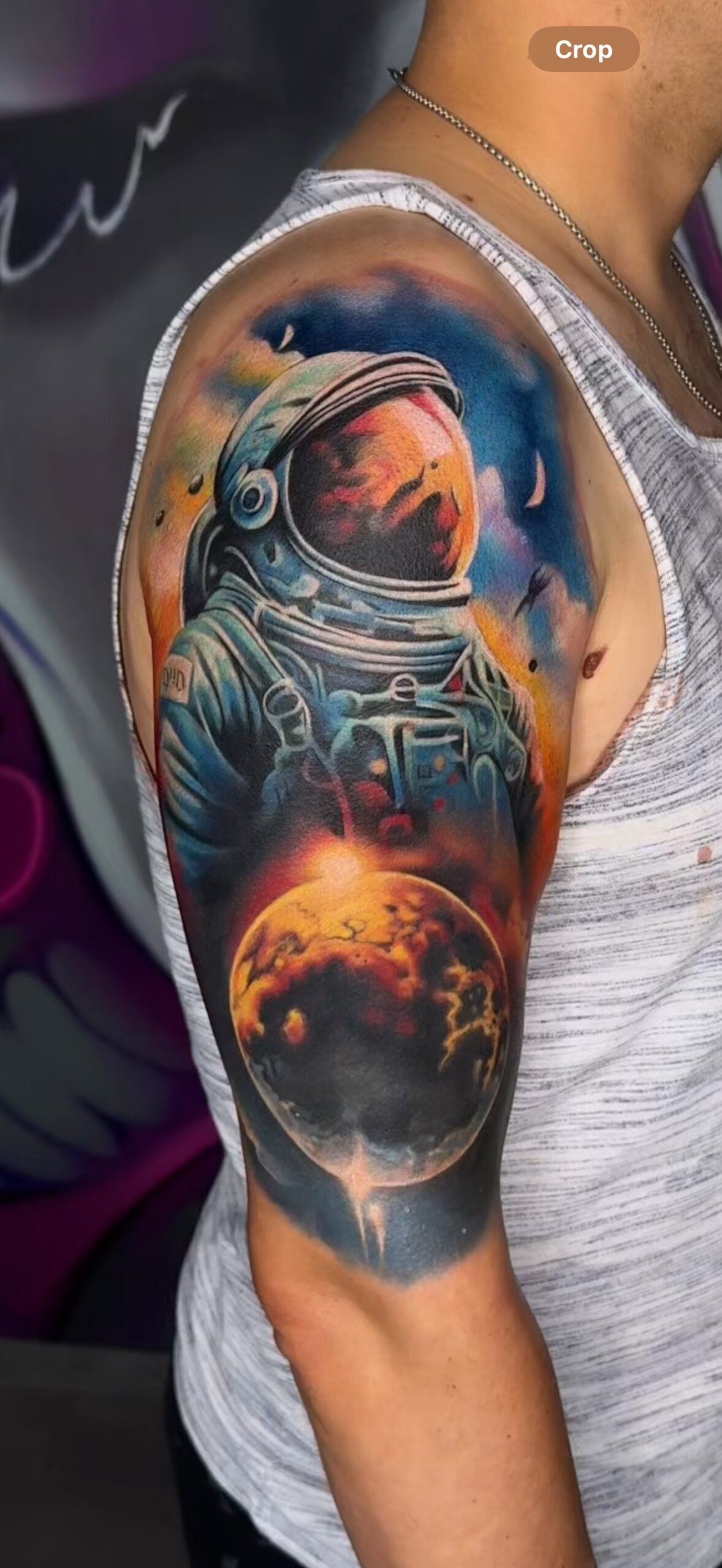 Astronauten-Tattoo auf Arm zeigt Weltraumszene.