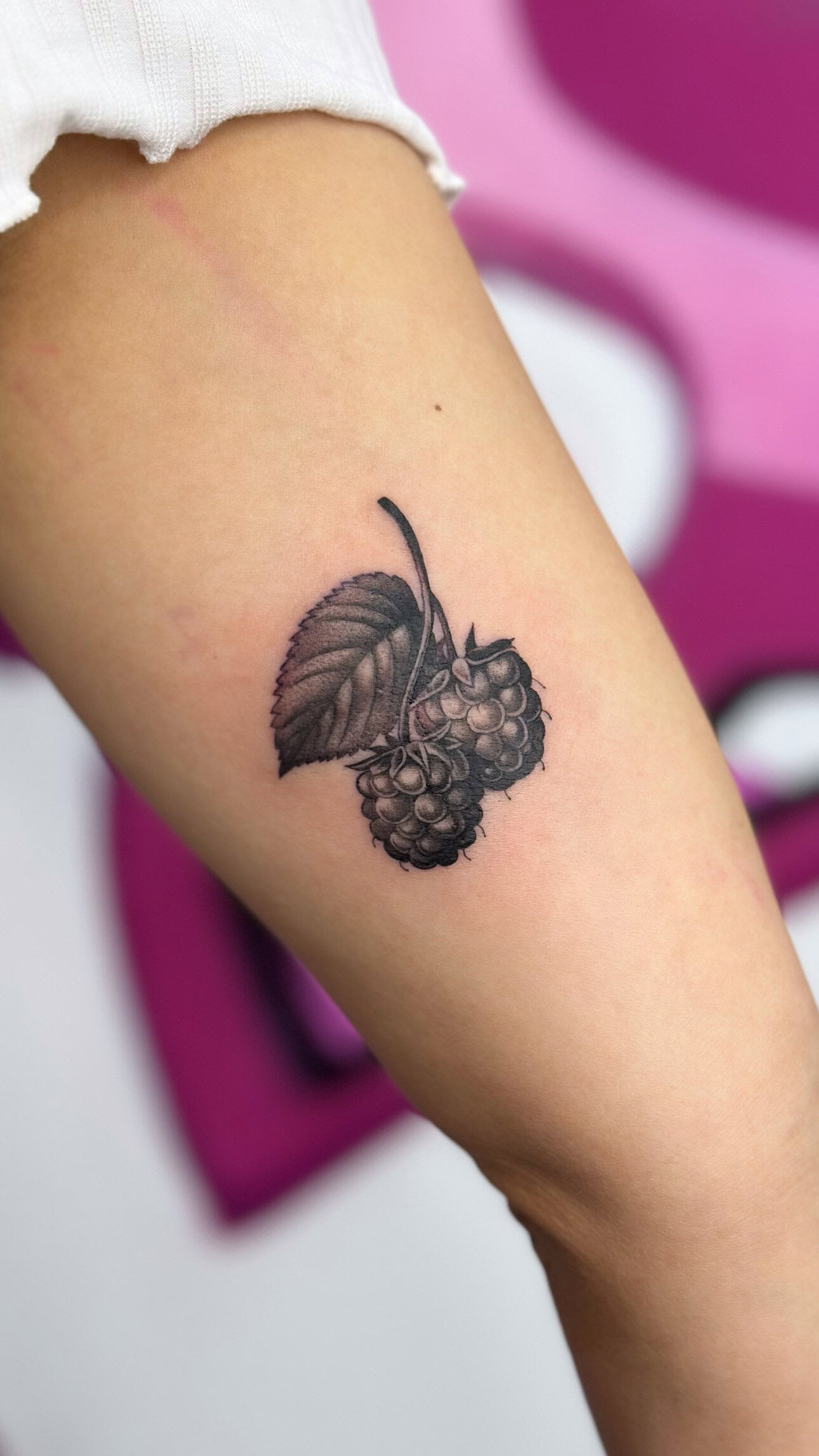 Bein-Tattoo mit Brombeeren und Blattmotiv.