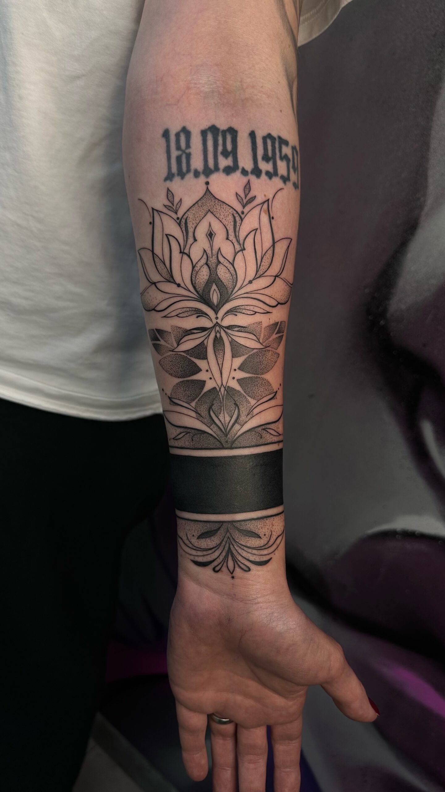 Arm mit floralem und Datums-Tattoo