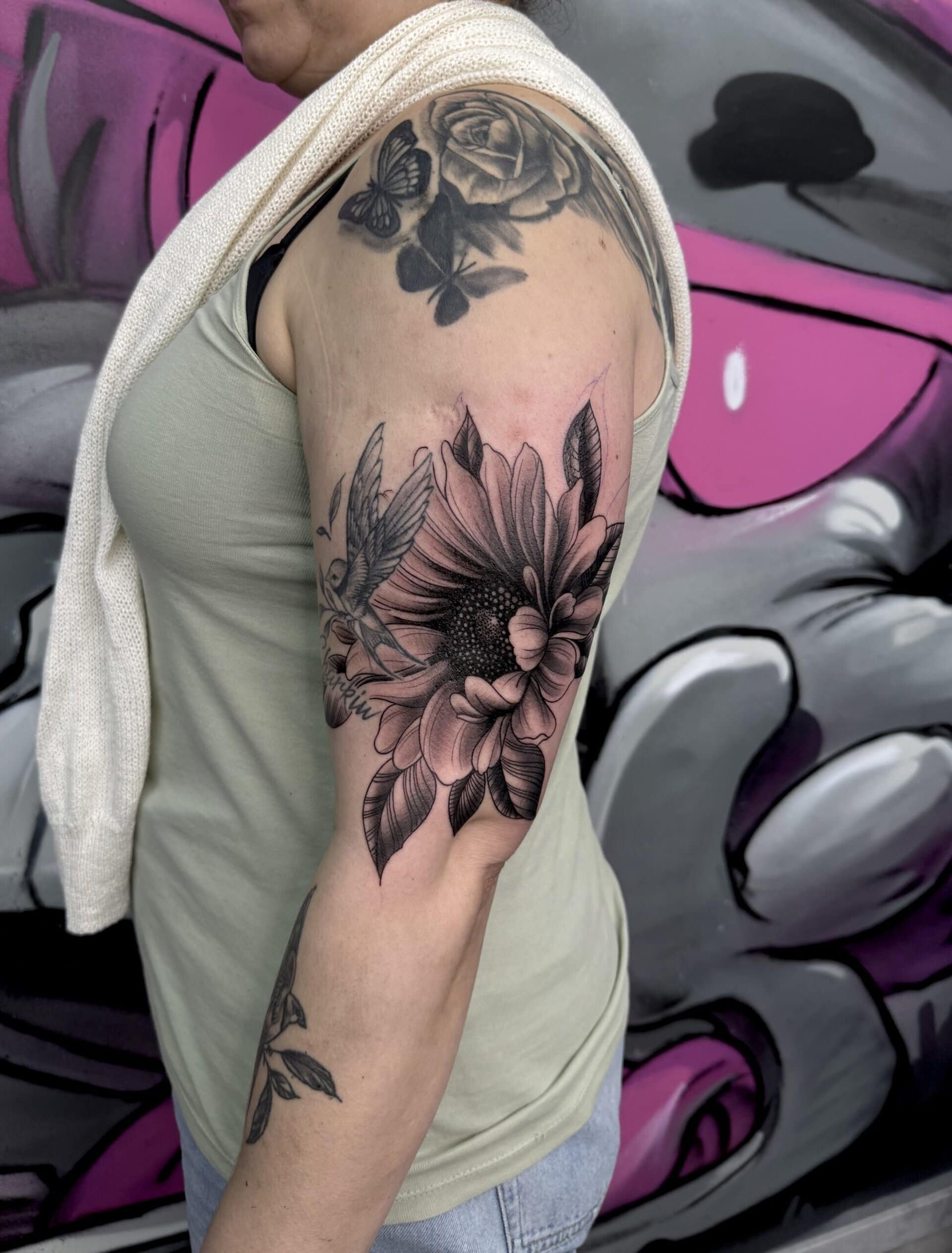 Frau mit Blumenkunst-Tattoo auf dem Oberarm.