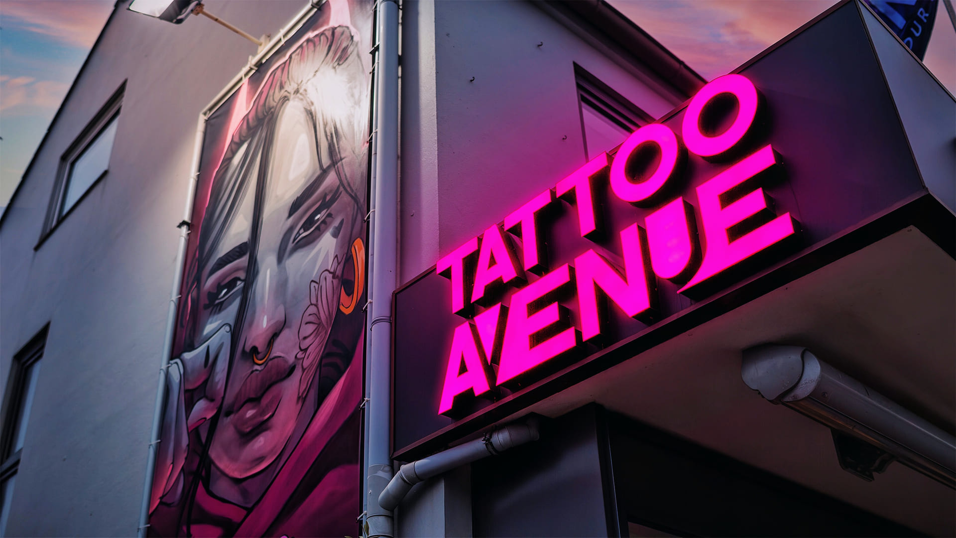 Wandleuchte, neonschrift Tattoo Avenue an Hauswand.