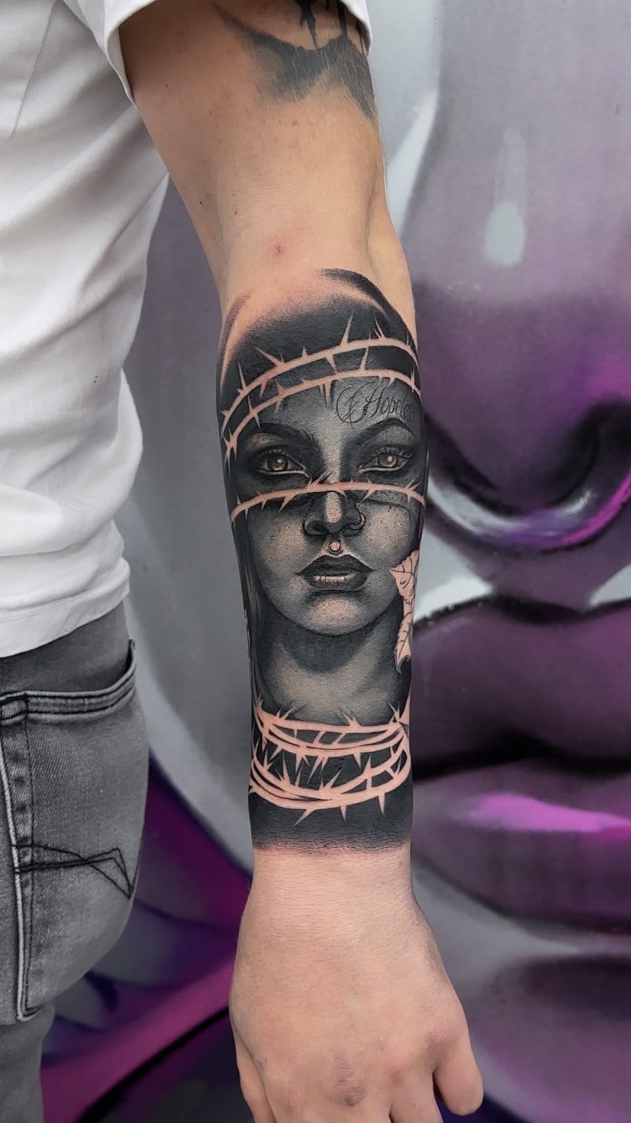 Tätowiertes Gesicht mit Dornenkrone auf Unterarm