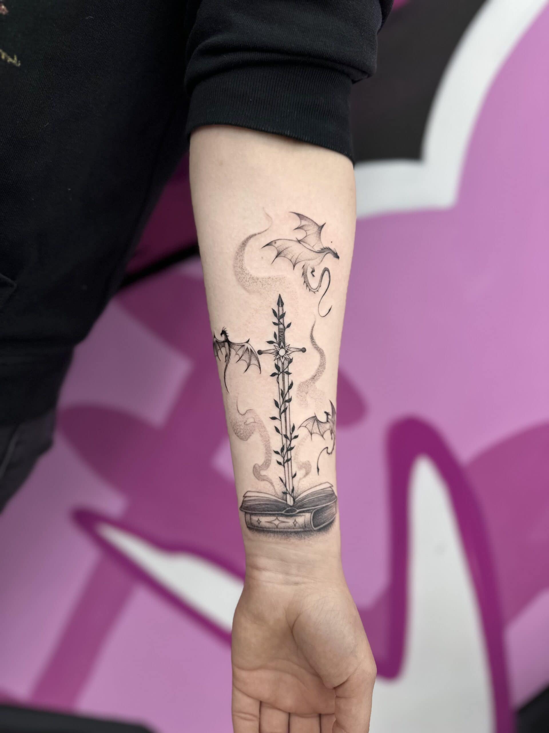 Tattoo eines Buches mit Schwert, Flammen und Game of Thrones Drachen.