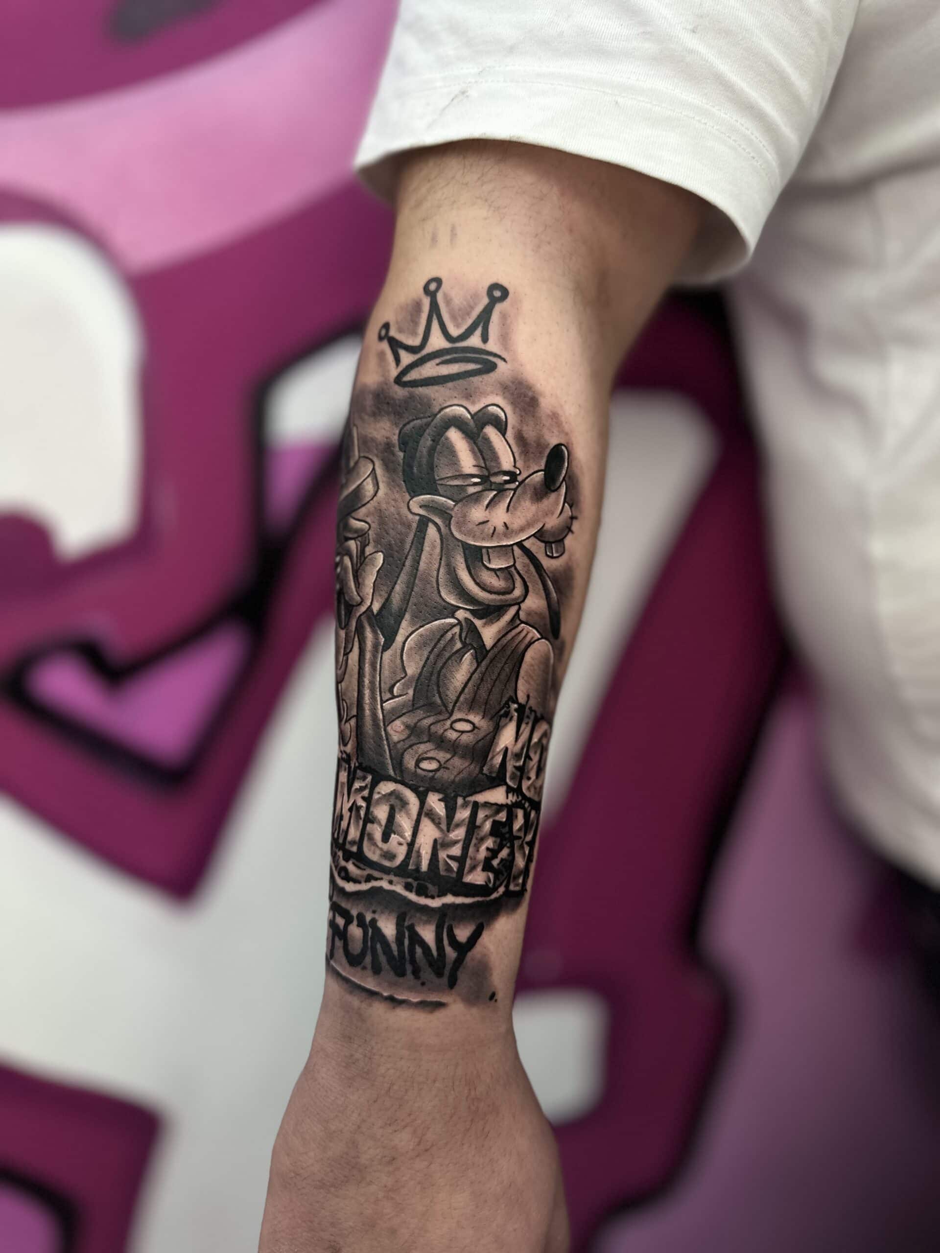 Goofy mit Krone Tattoo auf einem Unterarm.
